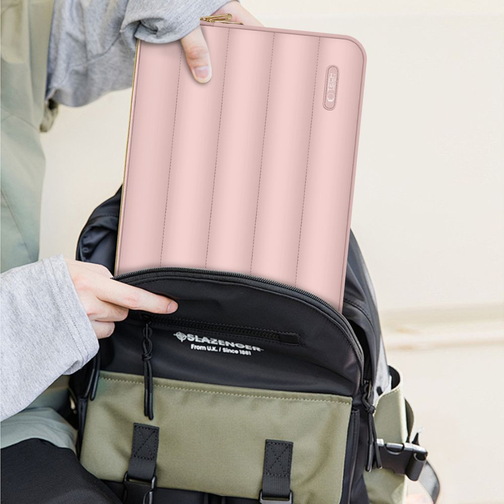 Persoon steekt een roze laptoptas in een zwarte en groene rugzak. De tas heeft verticale lijnen.