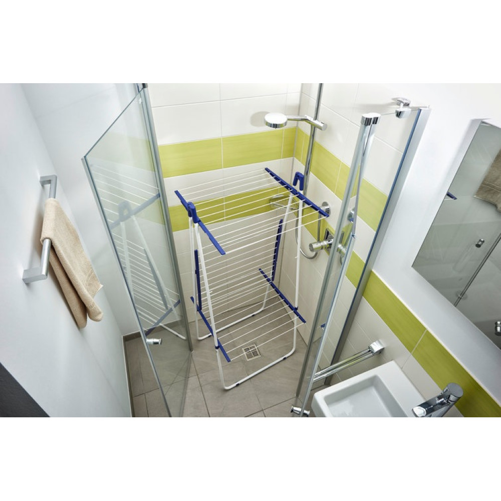 Łazienka z białą i zieloną kafelkową ścianą. Suszarka stoi pod prysznicem, a ręcznik wisi na ścianie.