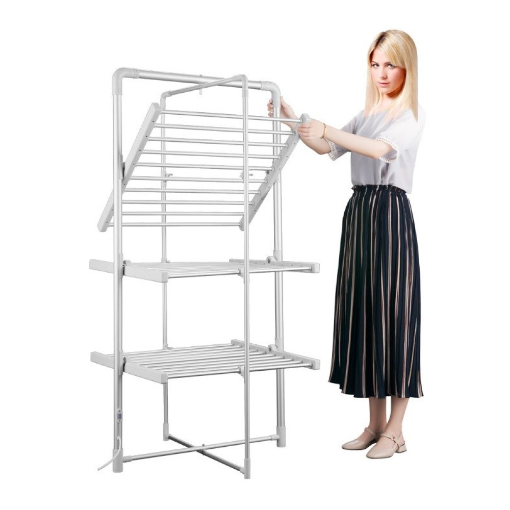 Kobieta reguluje biały, wielopoziomowy stojak do suszenia. Ma na sobie białą bluzkę i czarno-białą spódnicę w paski. Stojak jest srebrny.
