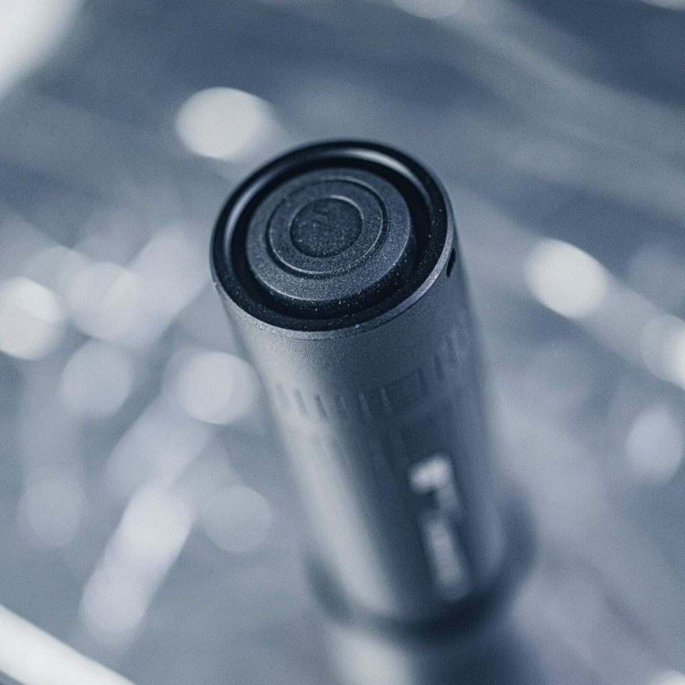 Zbliżenie cylindrycznego, ciemnoszarego obiektu ze współśrodkowymi okręgami. Rozmyte światło w tle.