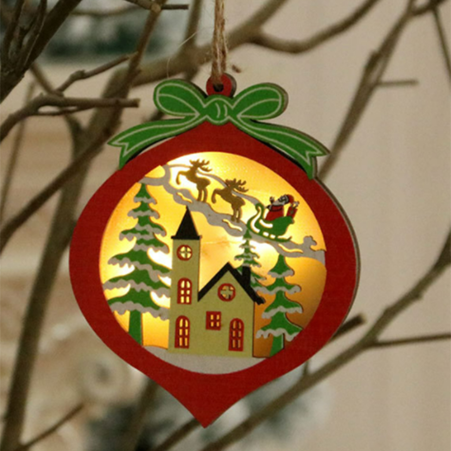 Ein roter Weihnachtsschmuck mit grüner Schleife. Innen fliegen der Weihnachtsmann im Schlitten über Kirche und Bäume.