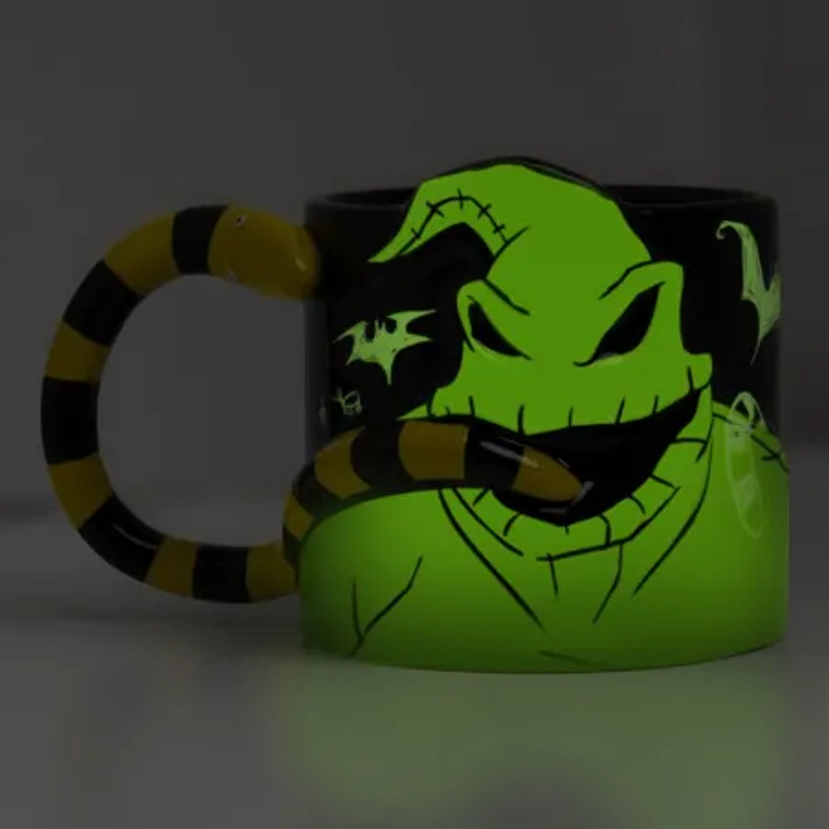 Kubek z Oogie Boogie z filmu Miasteczko Halloween. Kubek świeci na zielono, a uchwyt to wąż.