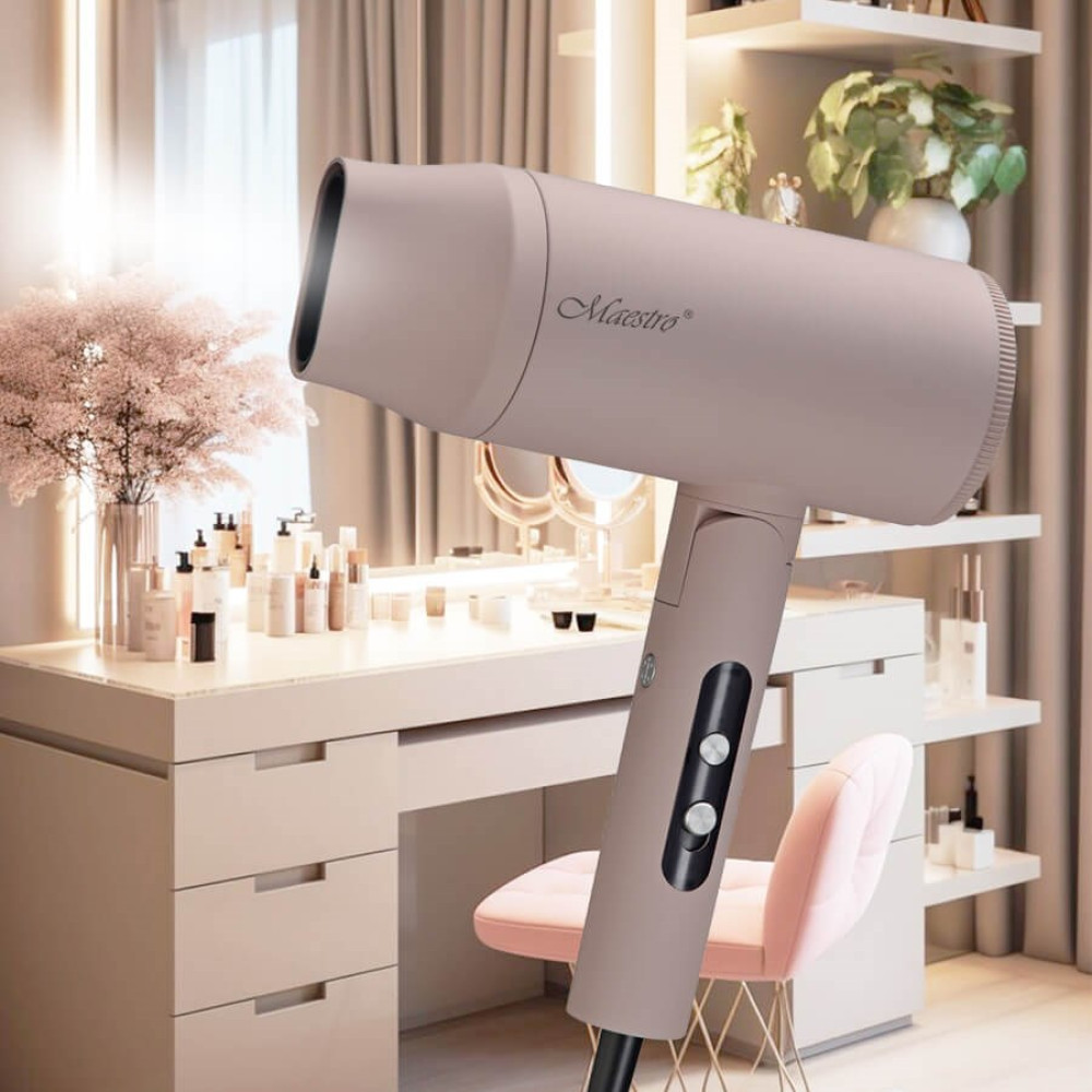 Beżowa suszarka do włosów marki Maestro stoi na toaletce. Różowe krzesło jest z przodu. Produkty do makijażu są na toaletce.