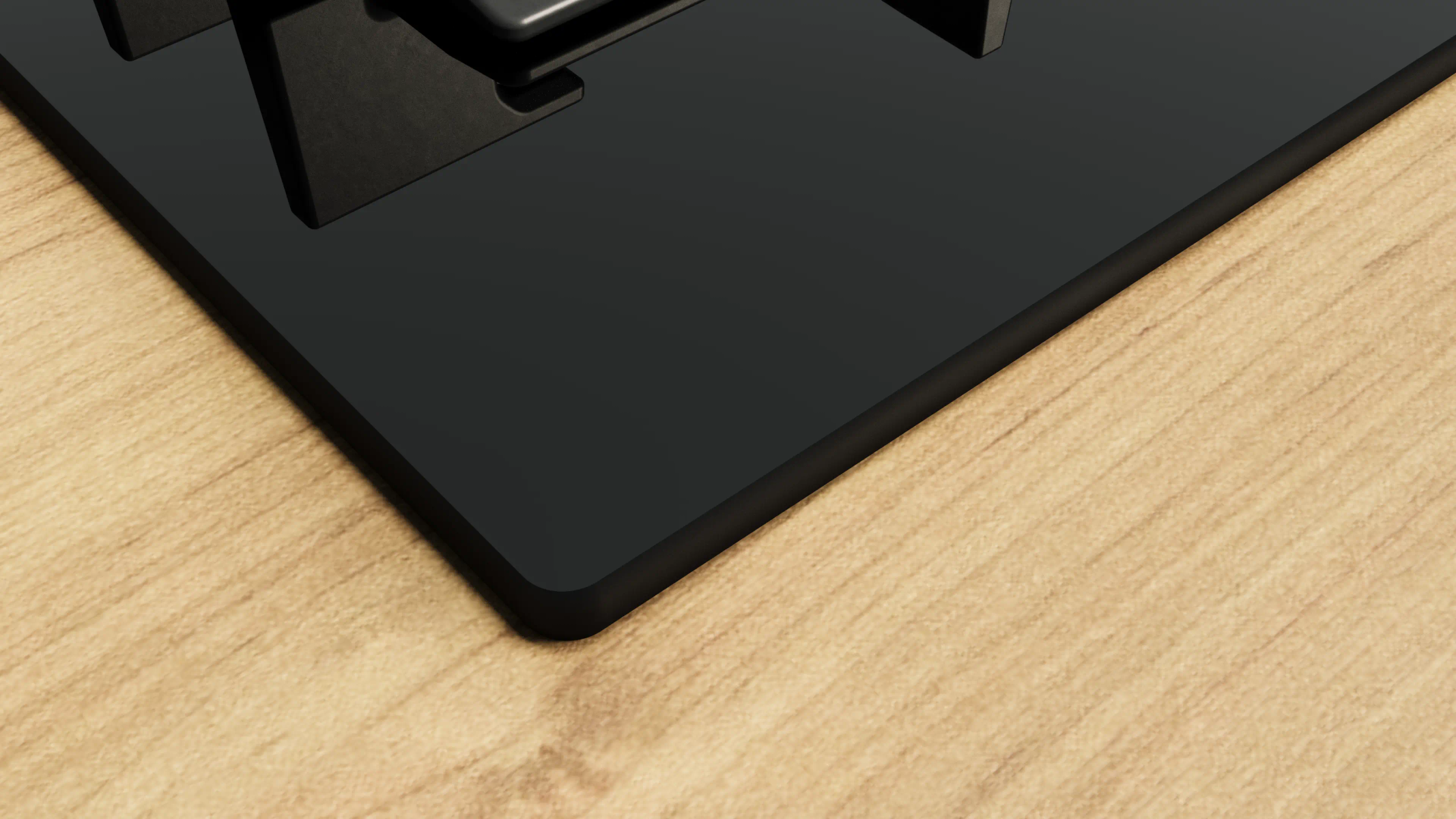 Zbliżenie czarnej płyty grzewczej na jasnym drewnianym blacie. Płyta grzewcza jest błyszcząca i odbija światło. Drewno ma usłojenie.