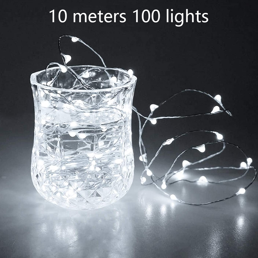 Ein Glas mit Wasser und Lichterketten darin. Einige Lichter befinden sich außerhalb des Glases. Der Hintergrund ist dunkel.