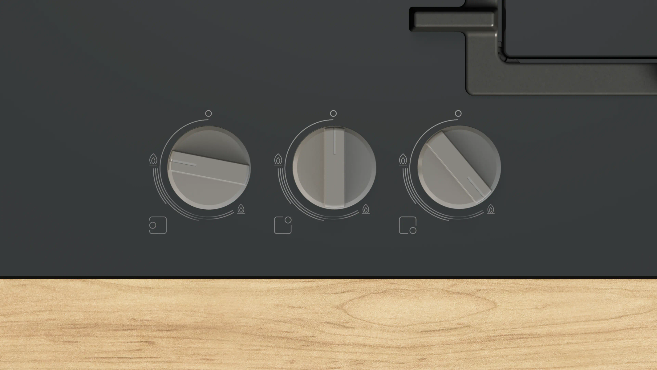 Zbliżenie płyty kuchennej z trzema pokrętłami. Pokrętła są srebrne z czarnymi oznaczeniami, na ciemnoszarym tle.