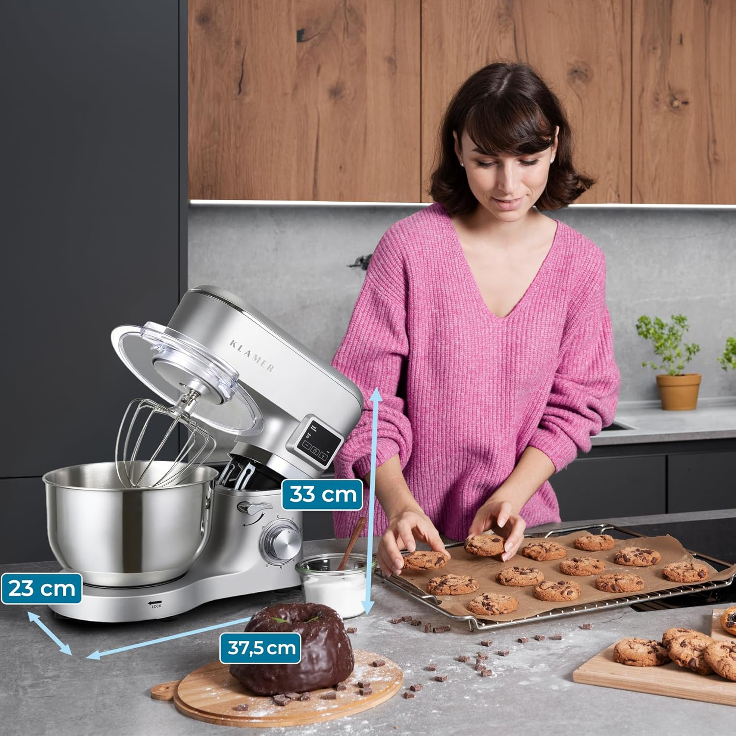 Frau backt mit einer Küchenmaschine. Kekse auf einem Blech. Enthält Maße des Mixers und einen Schokoladenkuchen.
