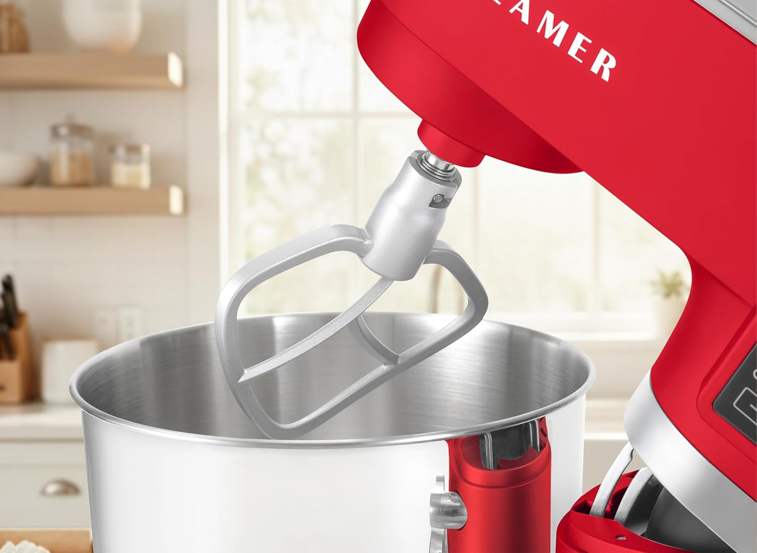 Ein roter Küchenmixer mit silbernem Rührbesen über einer Edelstahlschüssel. Der Hintergrund zeigt eine Küchenszene.