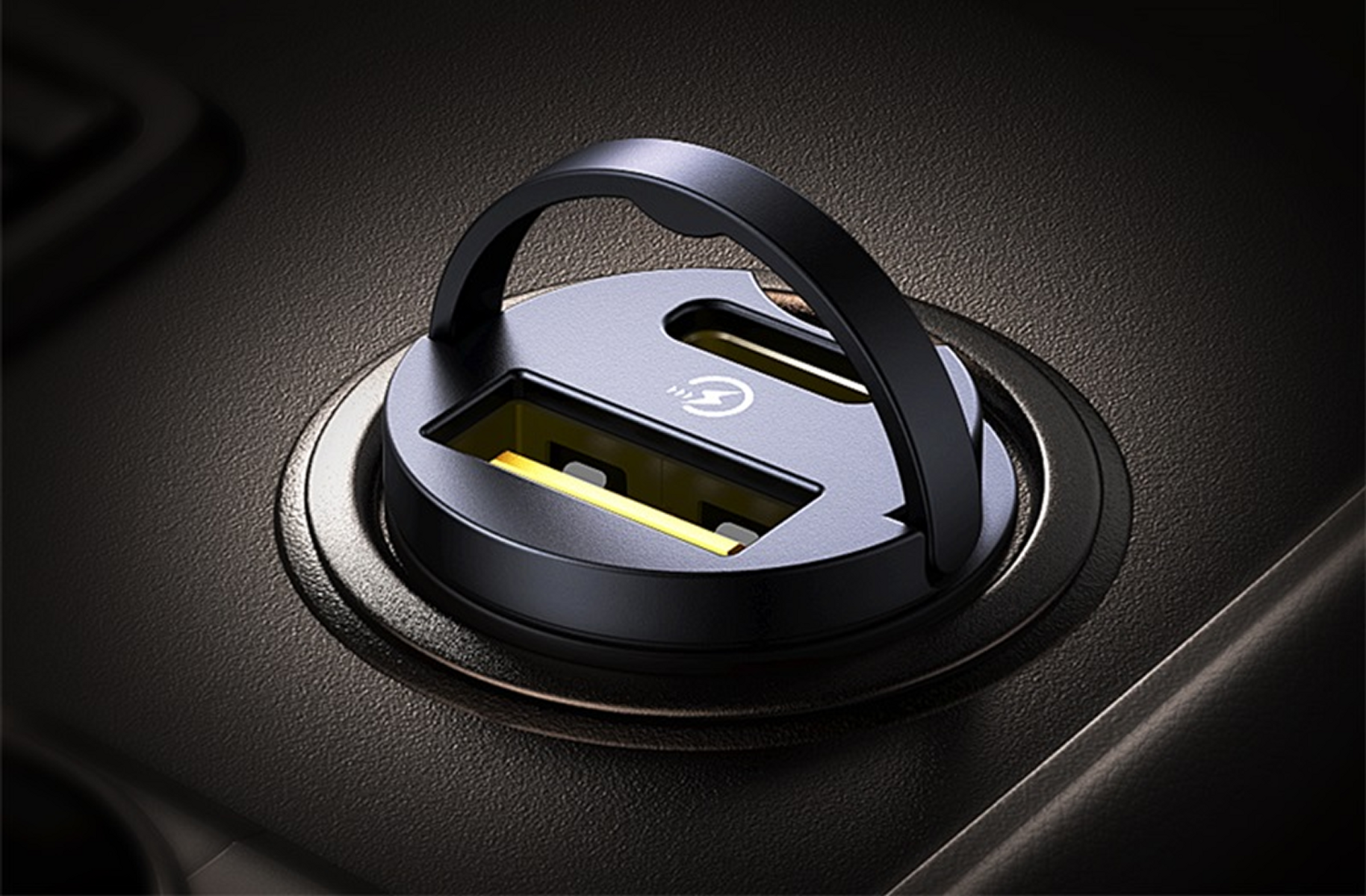 Un primo piano di un caricabatterie per auto nero con una maniglia. Ha due porte USB con interno giallo, in un ambiente scuro.