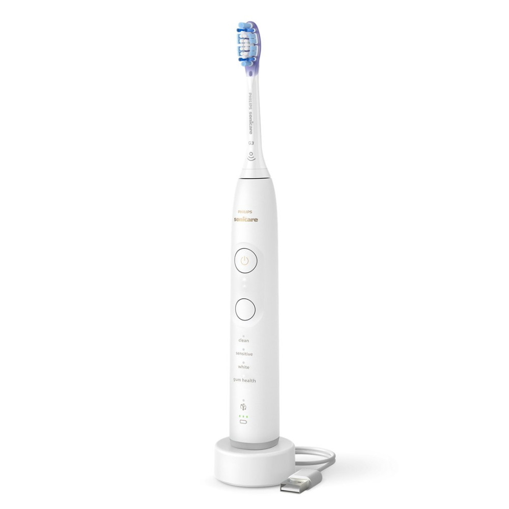 Biała elektryczna szczoteczka do zębów Philips Sonicare z niebiesko-białym włosiem, ładująca się na białej podstawie z kablem USB.