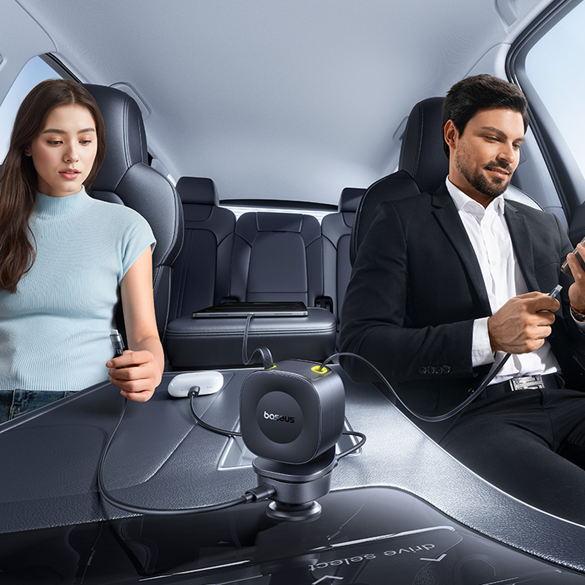 Dentro de un coche, un hombre y una mujer usan cargadores. Un cargador negro está entre ellos. Ambos sostienen teléfonos y cables.