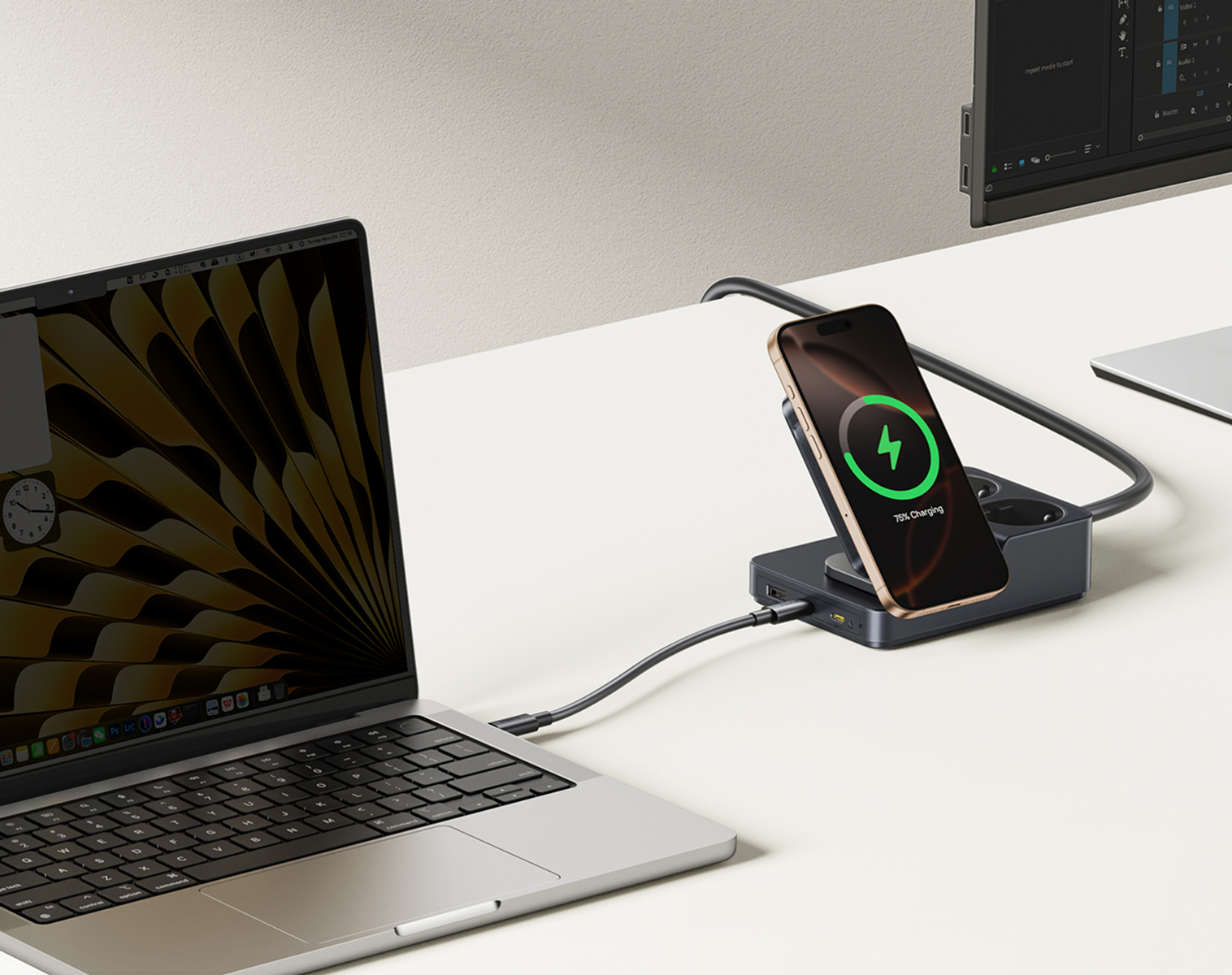 Un laptop e un telefono in carica su una scrivania. Il telefono mostra il 75% di carica. C'è una presa multipla e un monitor sullo sfondo.