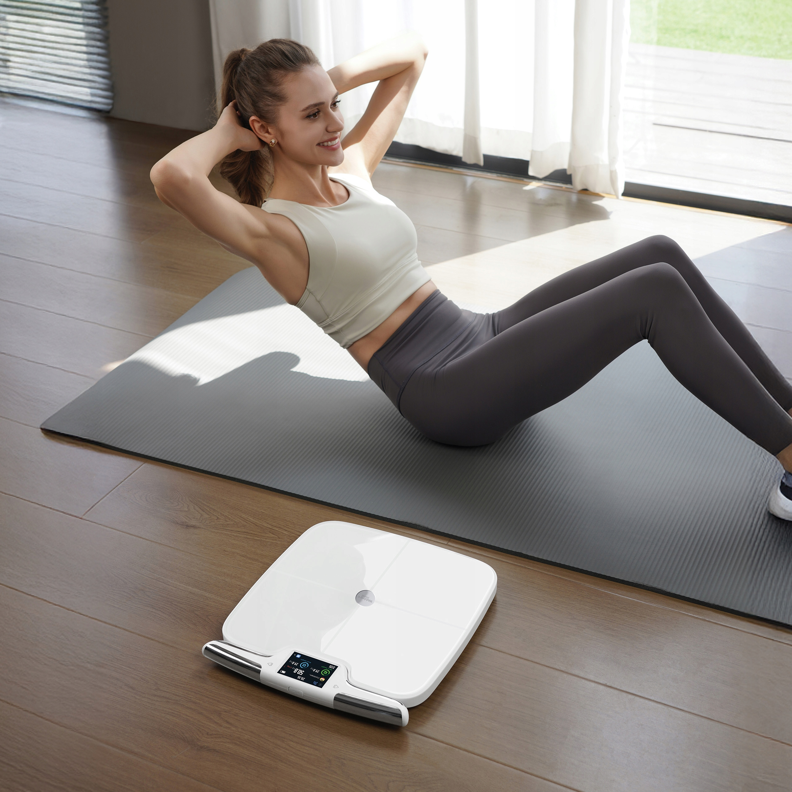Kobieta robi brzuszki na macie z wagą w pobliżu. Światło słoneczne wpada przez okno.