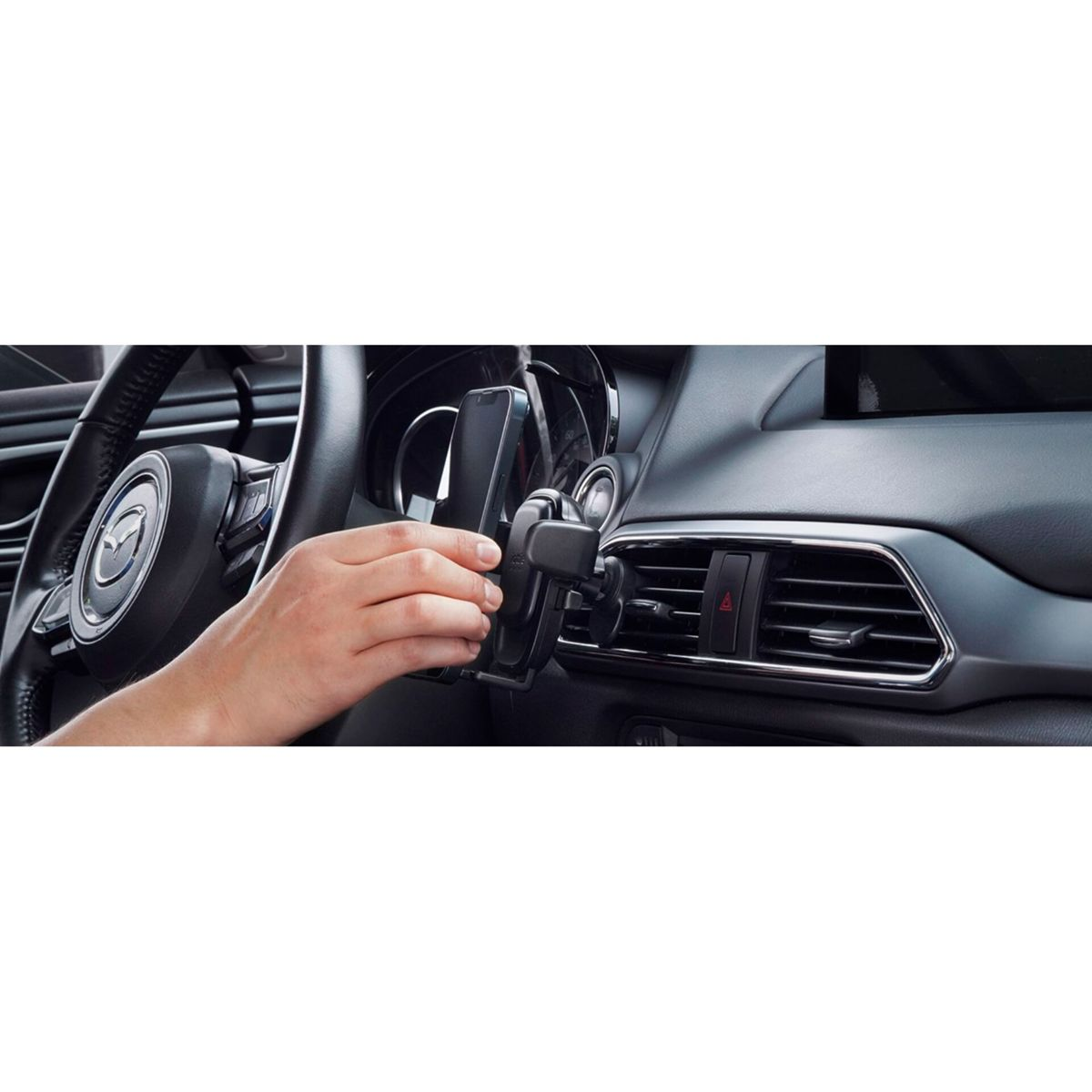 Mano che posiziona un telefono in un supporto per auto fissato alla presa d'aria. Sono visibili volante e cruscotto.