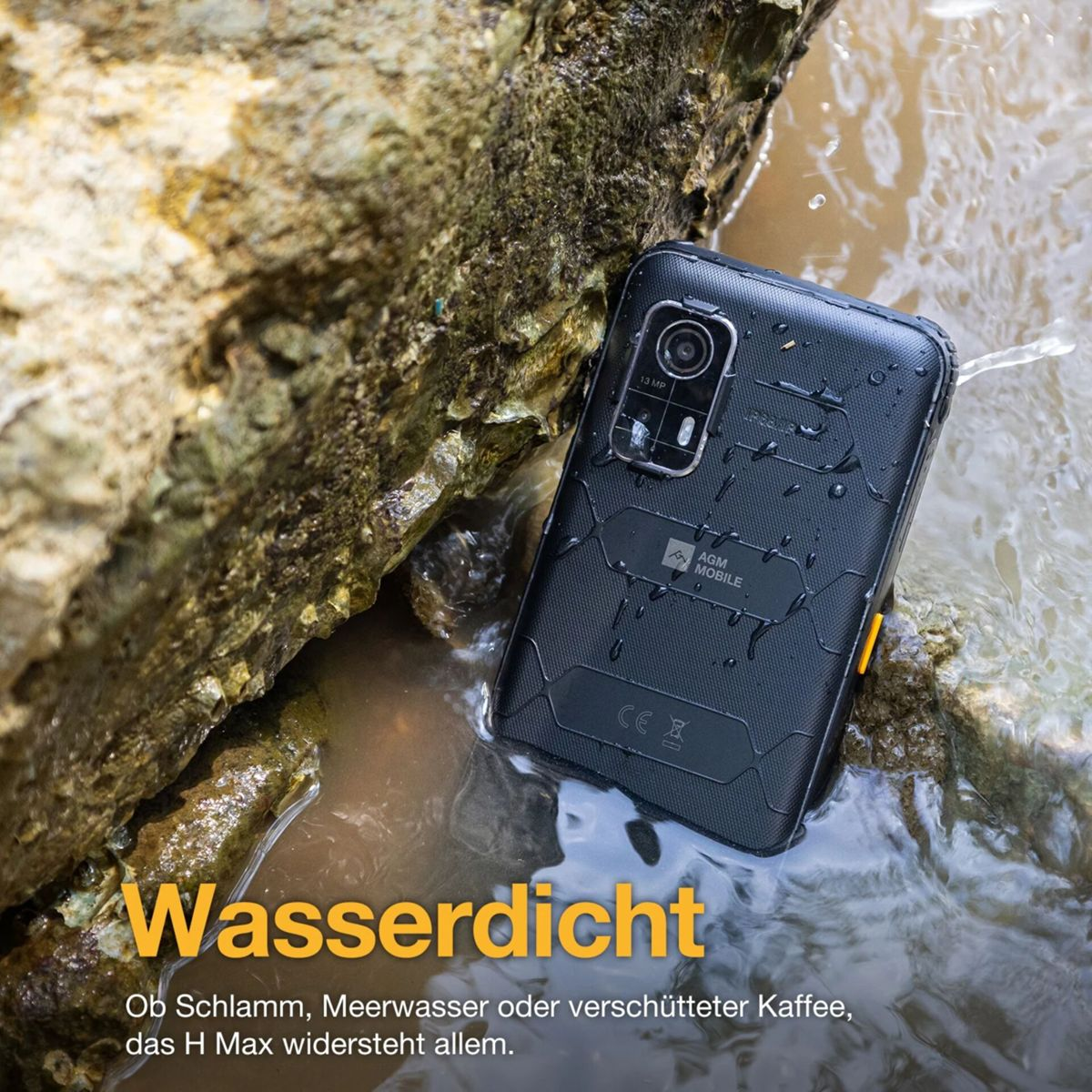 Uno smartphone nero, etichettato AGM Mobile, è bagnato nell'acqua. Riposa vicino a una roccia. Il telefono è impermeabile.