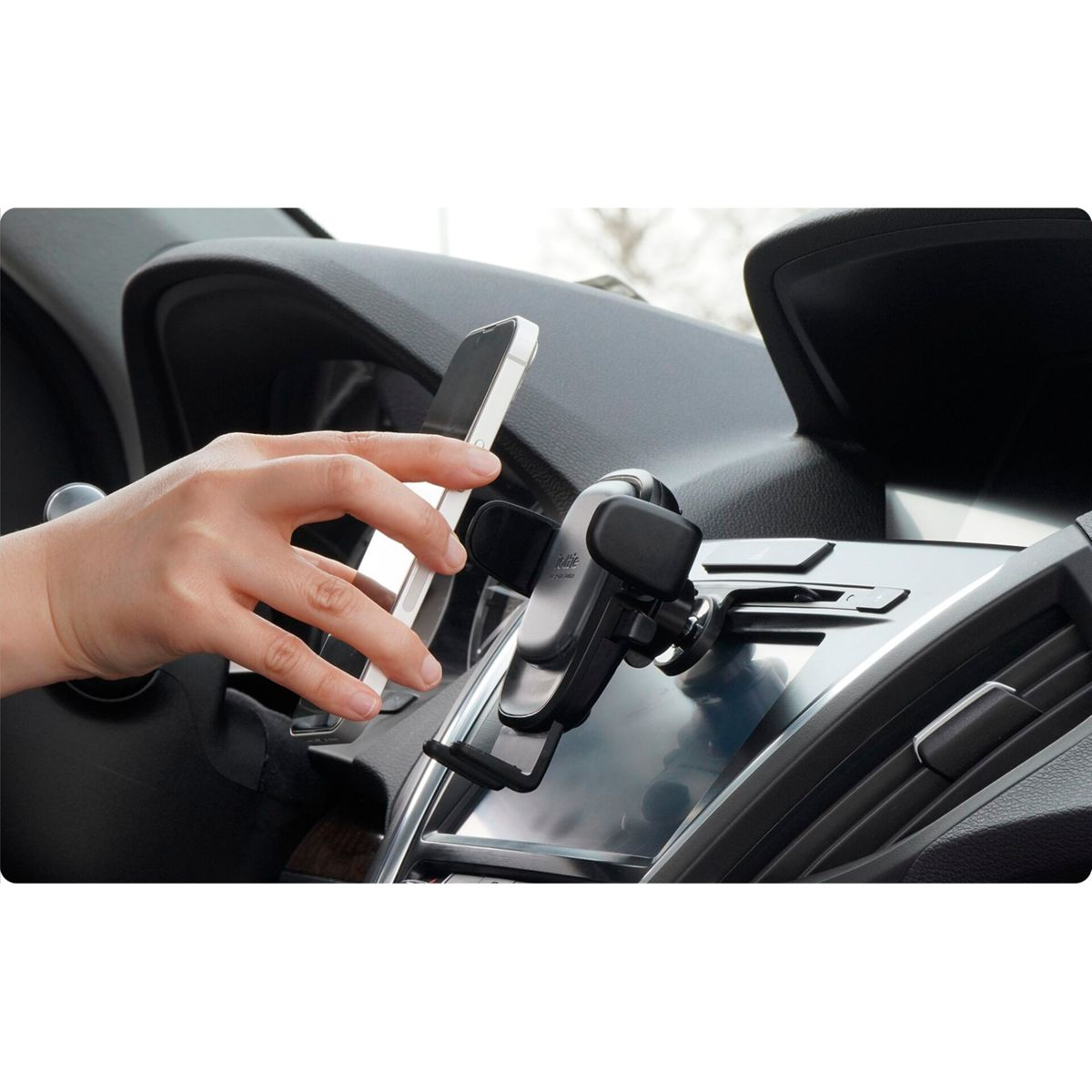 Eine Hand legt ein Smartphone in eine Autotelefonhalterung auf dem Armaturenbrett. Der Innenraum des Autos ist sichtbar.