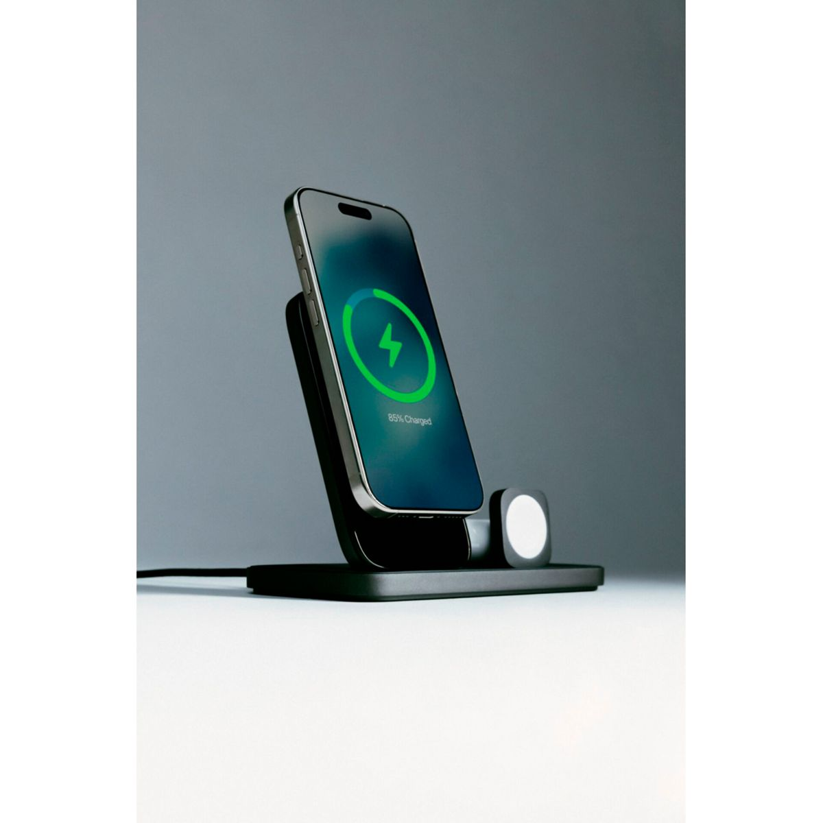 Ein Telefon wird auf einer schwarzen kabellosen Ladestation aufgeladen. Das Telefon zeigt 85 % geladen mit einem grünen Blitz an.