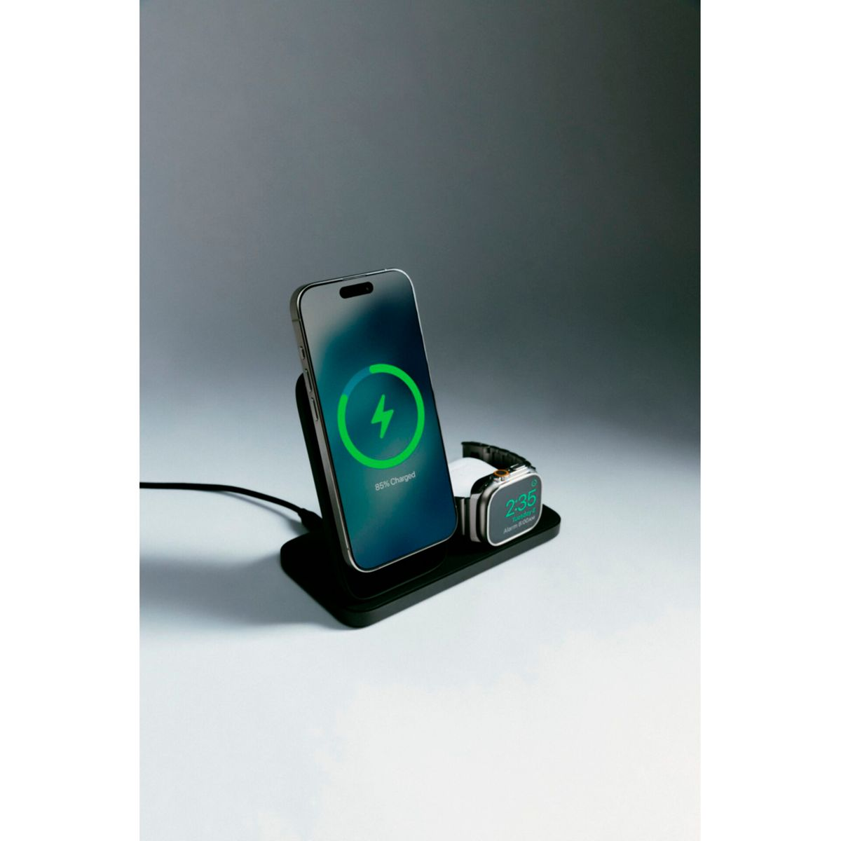 Ein Telefon und eine Smartwatch, die auf einer schwarzen Dockingstation geladen werden. Das Telefon zeigt 85% geladen an. Die Uhr zeigt die Zeit an.