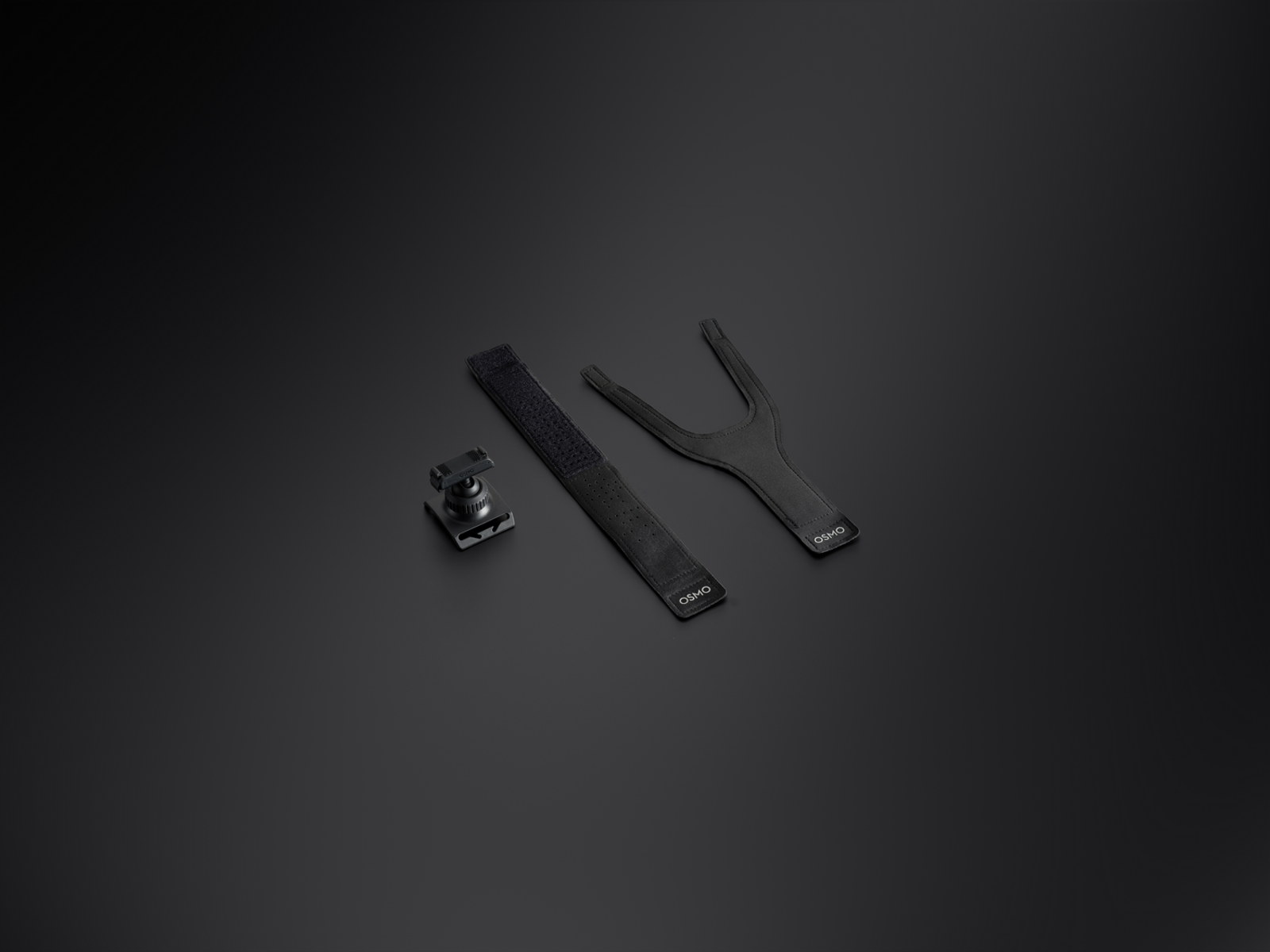 Tres accesorios negros de Osmo sobre una superficie oscura: un soporte de montaje, una correa de velcro y una correa en forma de Y, todos con el logotipo de Osmo.