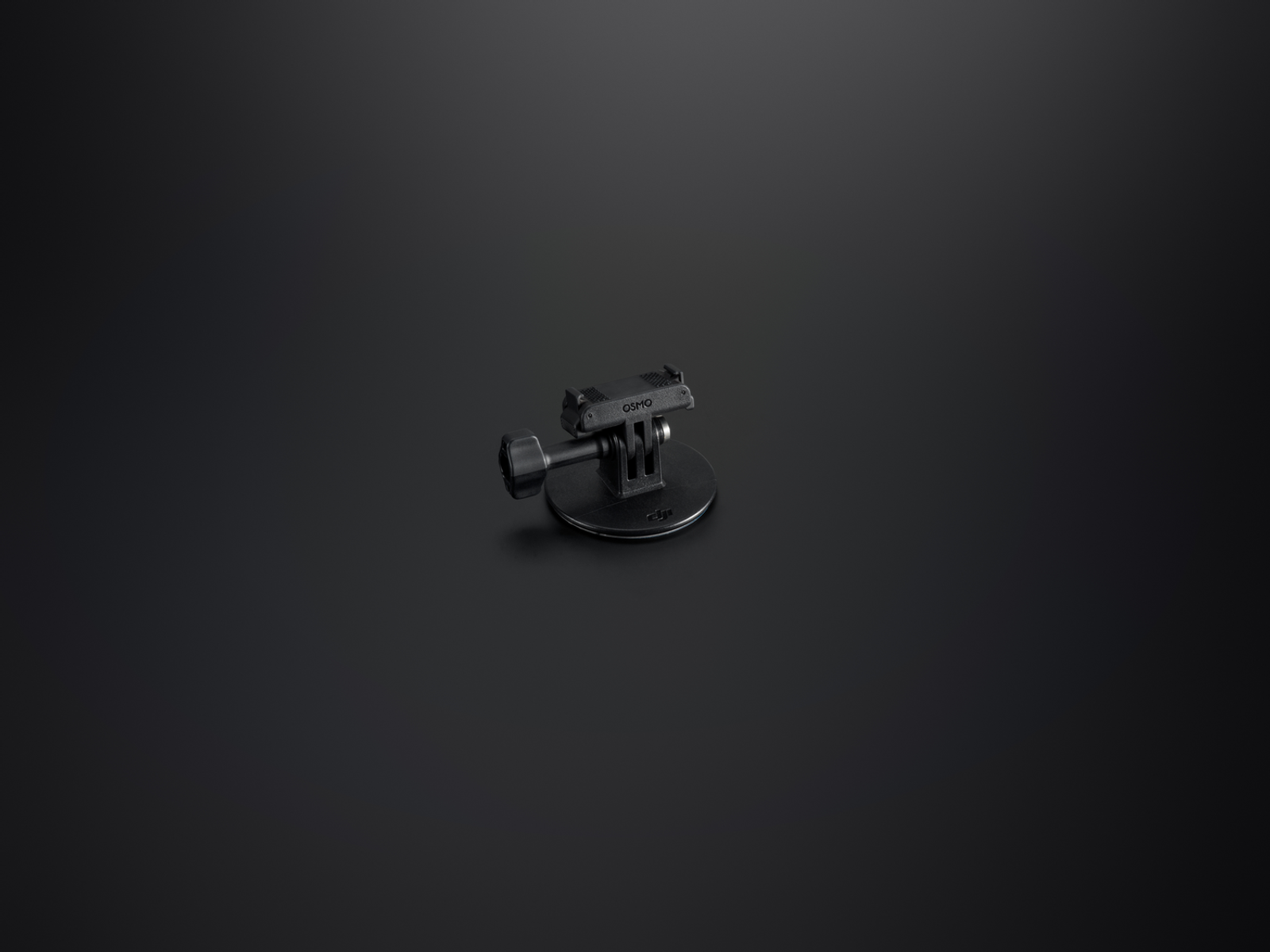 Un support de caméra Osmo noir sur une surface sombre. Il a une base, un bras et un support supérieur. Le fond est noir.