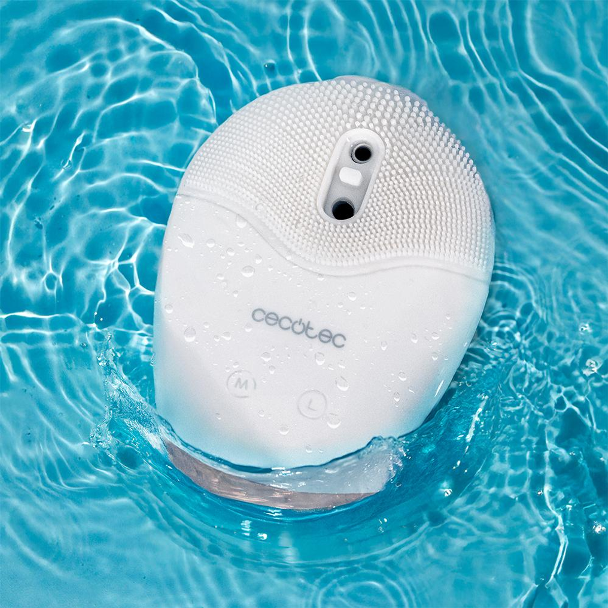 Un dispositivo di pulizia del viso Cecotec bianco in acqua blu. Il dispositivo è ovale con una parte superiore strutturata e pulsanti. Gocce d'acqua lo circondano.
