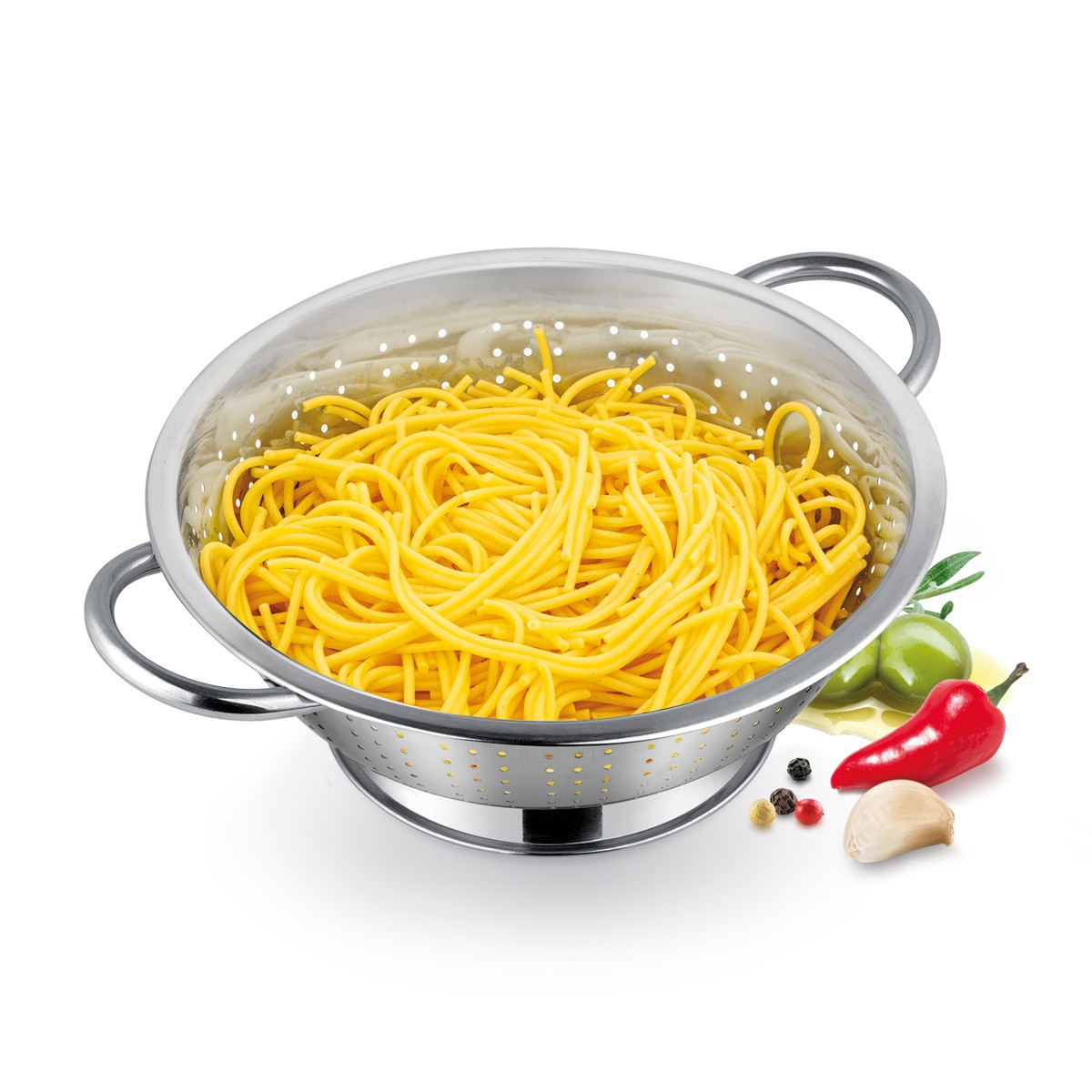Ein Sieb mit gelben Spaghetti. Daneben liegen Oliven, eine rote Paprika, Knoblauch und Pfefferkörner auf weißem Untergrund.