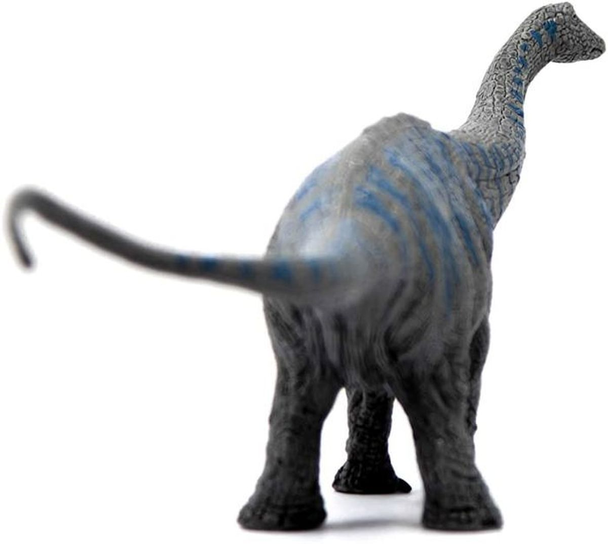 Un giocattolo di dinosauro grigio con strisce blu. Il dinosauro ha un collo e una coda lunghi. È in piedi su una superficie bianca.