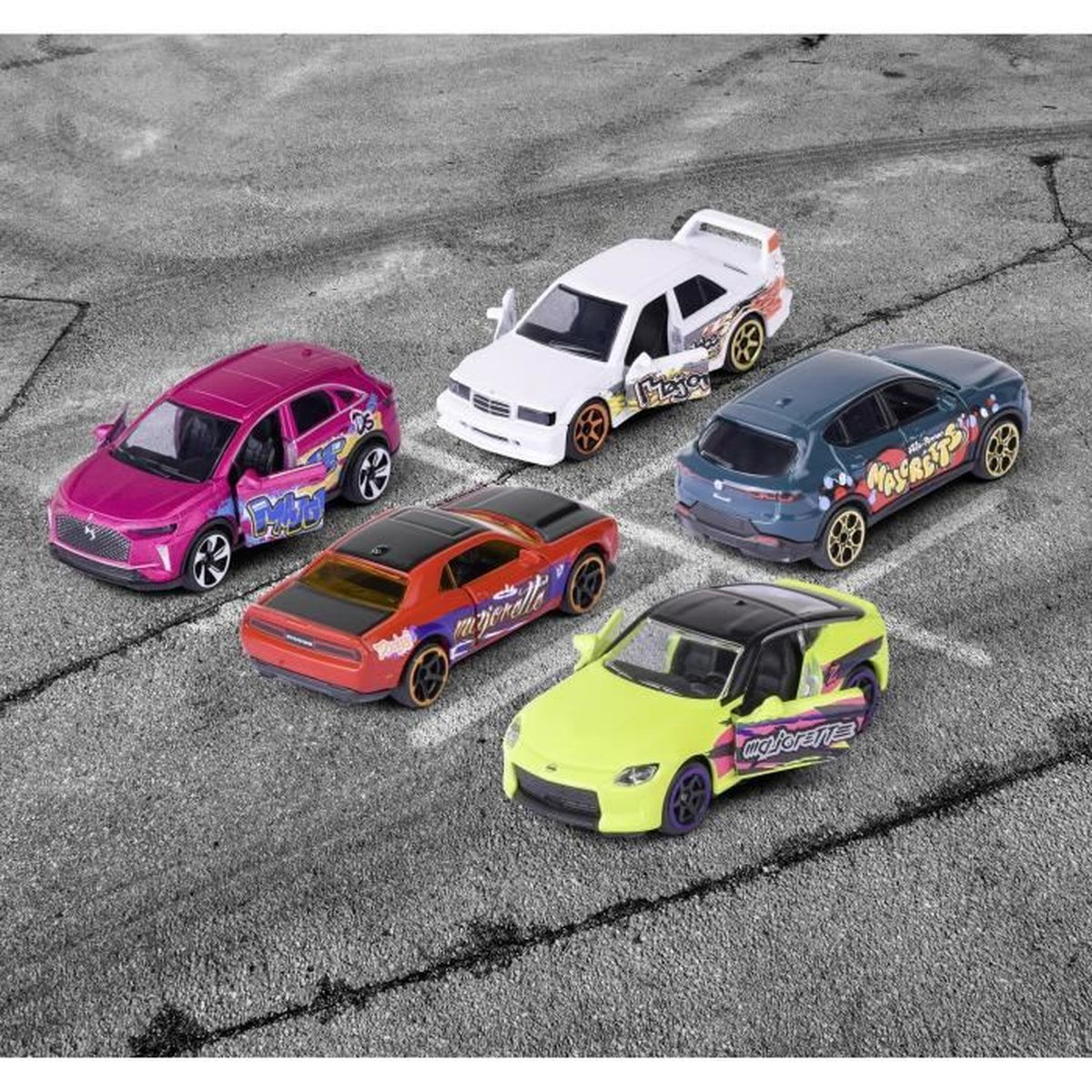 Cinco coches de juguete sobre asfalto. Colores: rosa, blanco, rojo, verde y azul oscuro. Cada uno tiene calcomanías únicas y puertas abiertas.