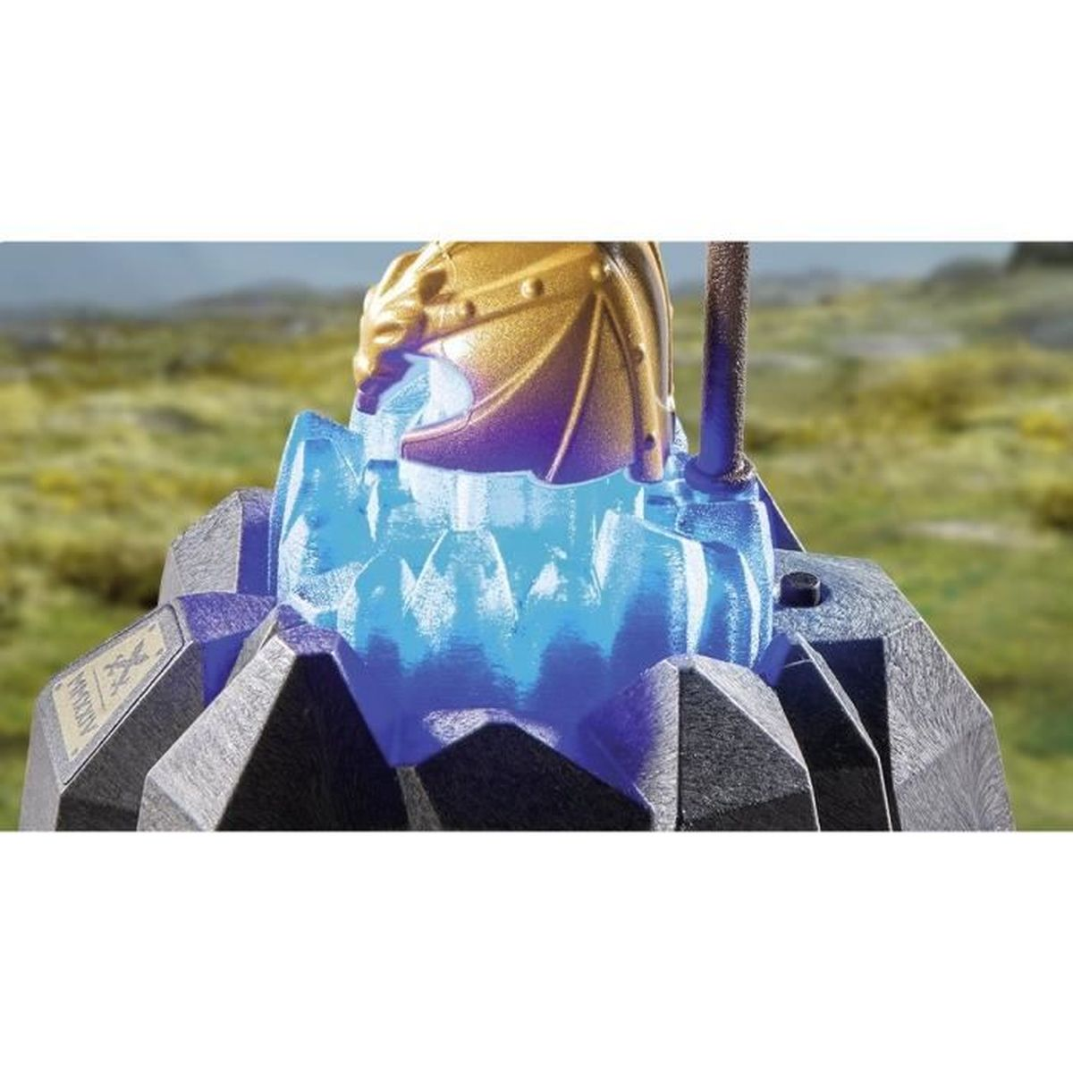 Ein goldener Drachenhelm thront auf einer blauen Kristallstruktur. Er steht auf einem dunkelgrauen, geometrischen Sockel. Grüne Hügel im Hintergrund.