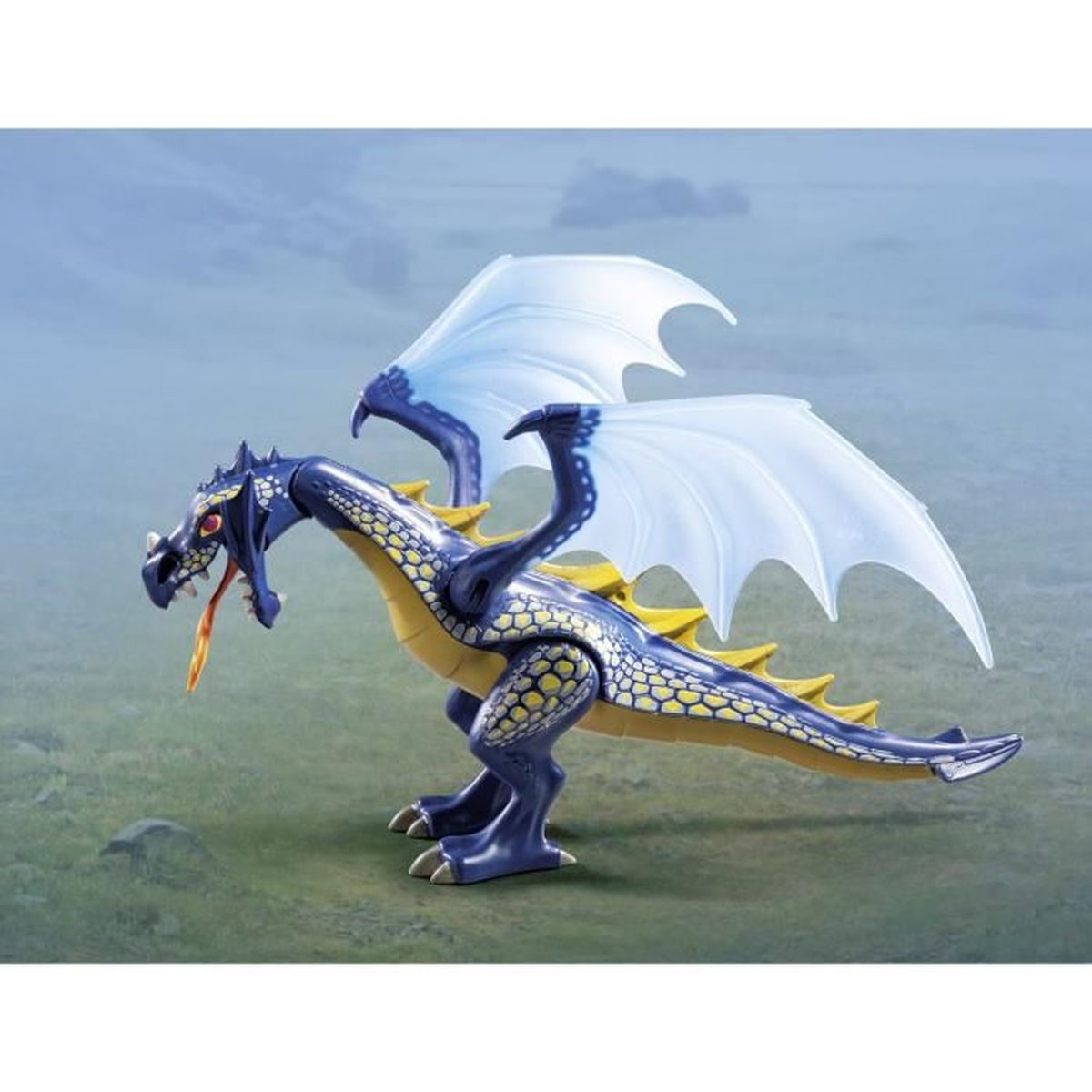 Ein blau-gelber Spielzeugdrache mit weißen Flügeln steht auf grünem Boden. Es hat einen offenen Mund mit orangefarbener Flamme.