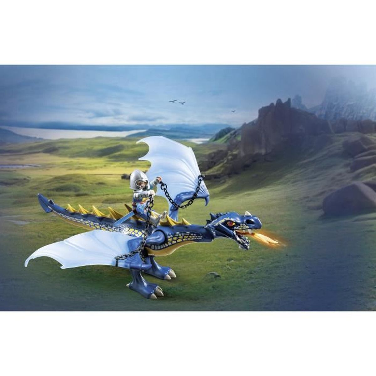 Ein Spielzeugdrache mit einem Ritter, der ihn reitet und Feuer speit. Er hat weiße Flügel und steht vor einer grünen Wiese und einem Berg.