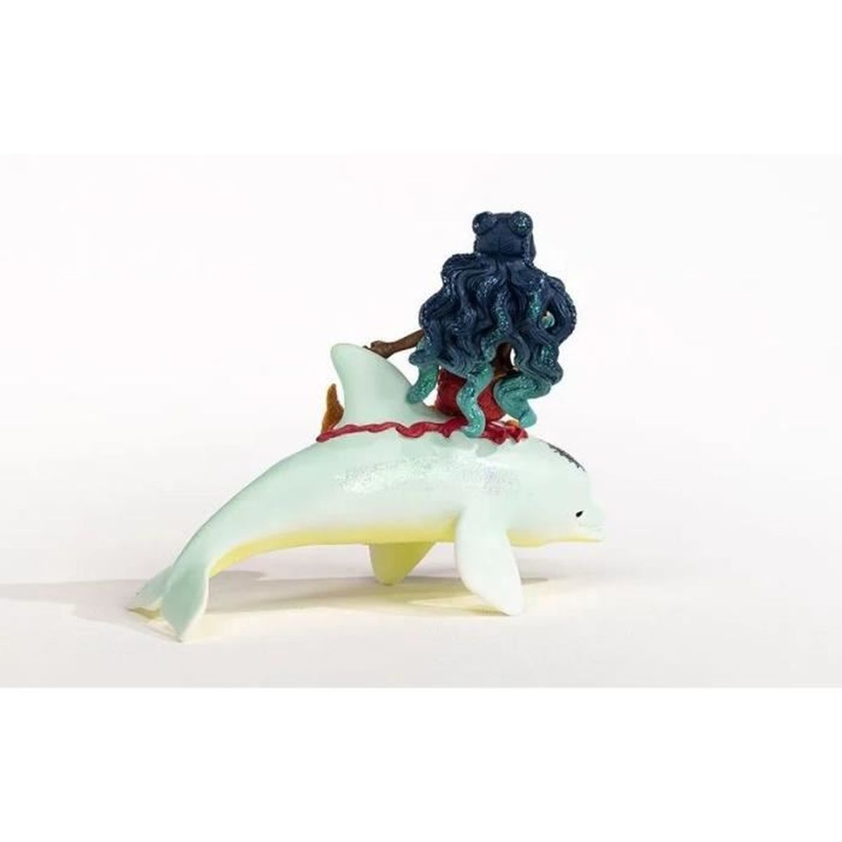 Eine Figur zeigt eine blauhaarige, oktopusartige Figur, die auf einem Delfin reitet. Der Delfin ist weiß mit gelben Akzenten, auf weißem Hintergrund.