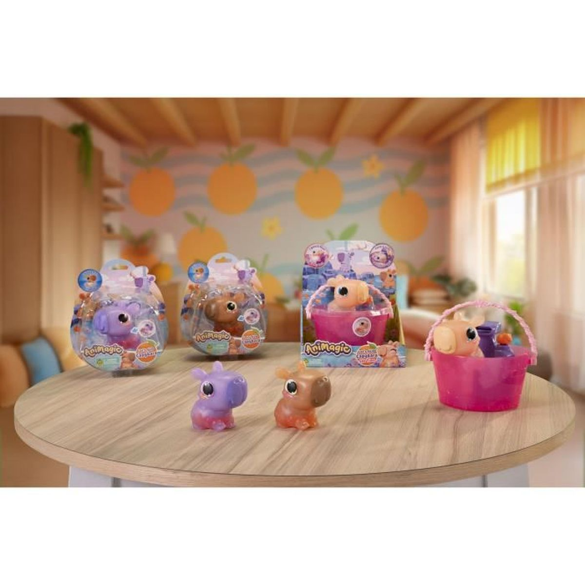 Auf einem Holztisch sind Animagic-Spielzeuge ausgestellt: Flusspferde in Verpackungen und lose. Ein rosa Korb mit einem Flusspferd und ein Hintergrund mit orangenen Formen.