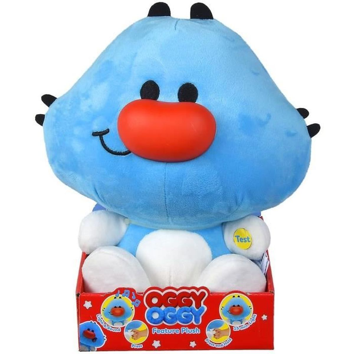 Ein blaues Oggy-Plüschtier mit roter Nase und schwarzen Augen sitzt in einer roten Box mit der Aufschrift 'Oggy'. Das Spielzeug hat weiße Pfoten.