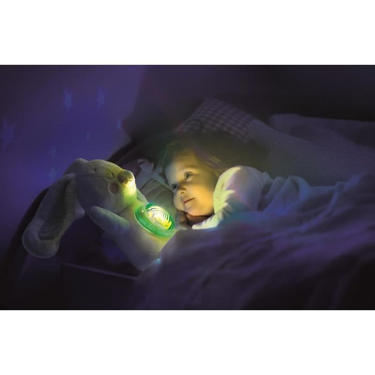 Un bambino a letto, illuminato da un giocattolo luminoso. Un coniglio di peluche tiene una luce, il bambino la guarda. Stelle sul muro.