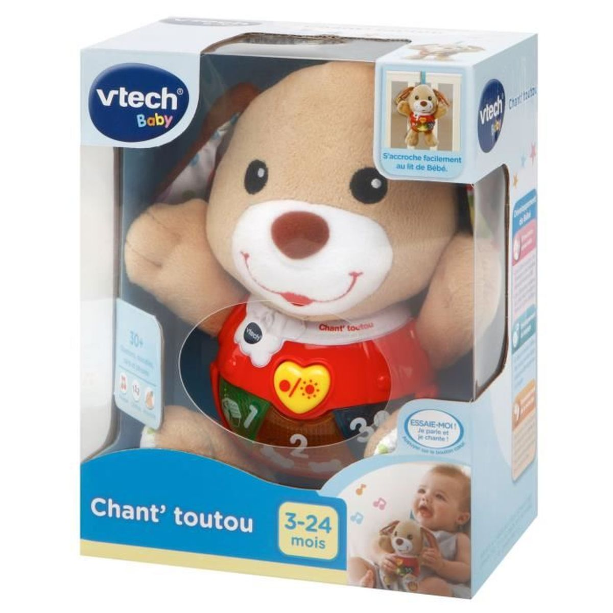 Ein Vtech Baby Hundespielzeug in einer Schachtel. Das Spielzeug ist braun mit einem roten Hemd. Auf der Schachtel steht 'Chant' toutou' und '3-24 mois'.