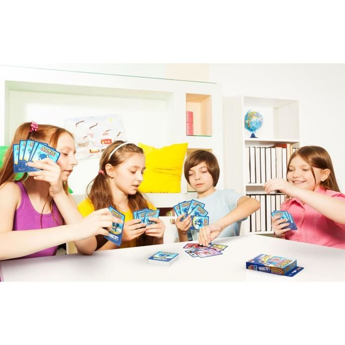 Cztery dzieci grają w karty. Trzymają karty z Soniciem. Karty na stole i w rękach.