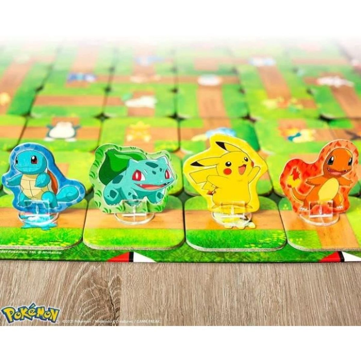 Cztery figurki Pokemon na planszy: Squirtle, Bulbasaur, Pikachu i Charmander. Zielone tło labiryntu.