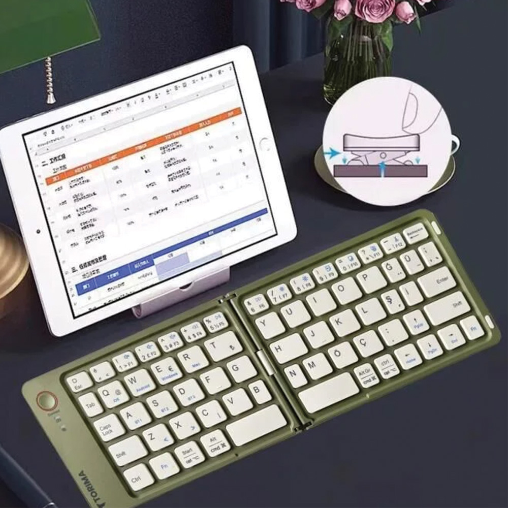 Hesap tablosu olan bir tablet, yeşil katlanır bir klavye ve koyu bir yüzeyde bir diyagram, arkada çiçekler.