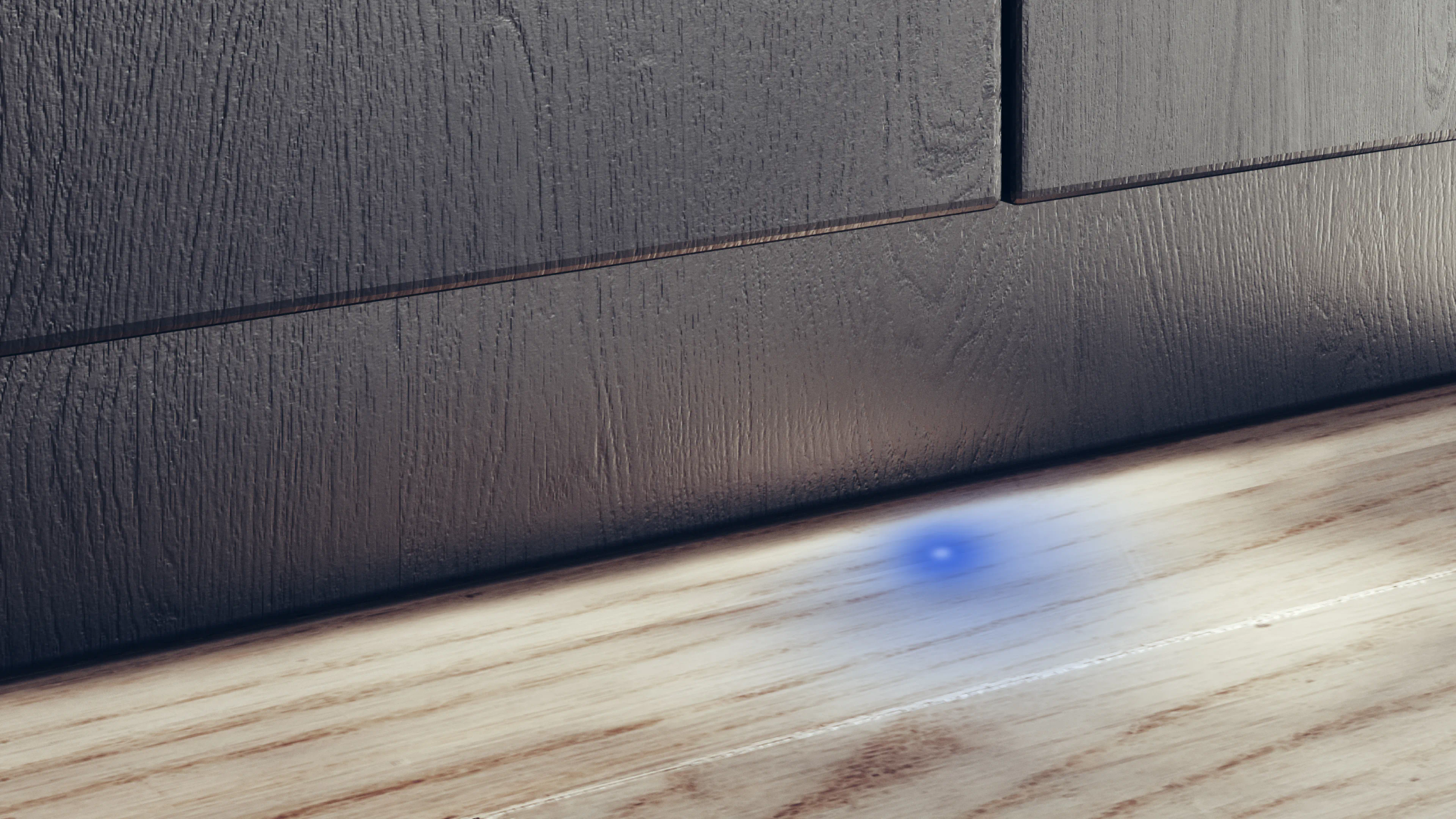 Drewniana podłoga z ciemną szafką. Na podłodze widoczny jest niebieski punkt światła, dodający scenie koloru.