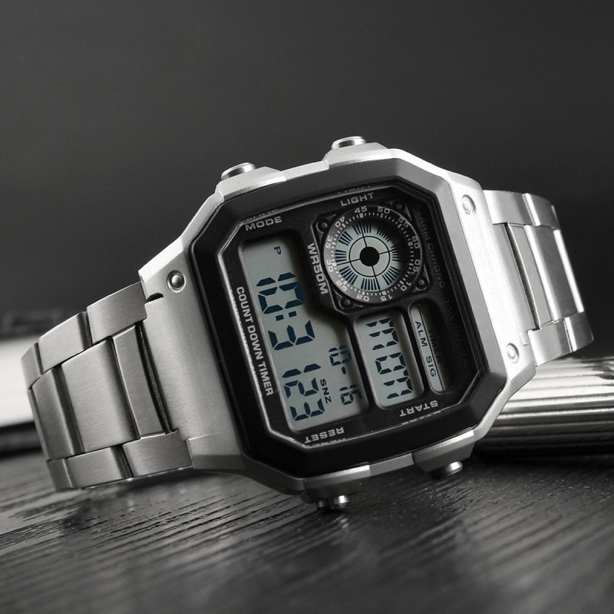 Eine silberne Digitalarmbanduhr liegt auf einer dunklen Oberfläche. Die Uhr zeigt Uhrzeit und verschiedene Funktionen an.