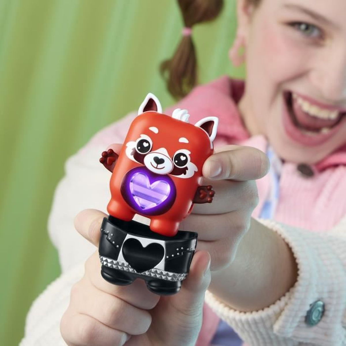 Ein lächelndes Mädchen hält ein rotes Panda-Spielzeug. Das Spielzeug hat ein leuchtendes Herz auf dem Bauch, das auf schwarzen Shorts sitzt.