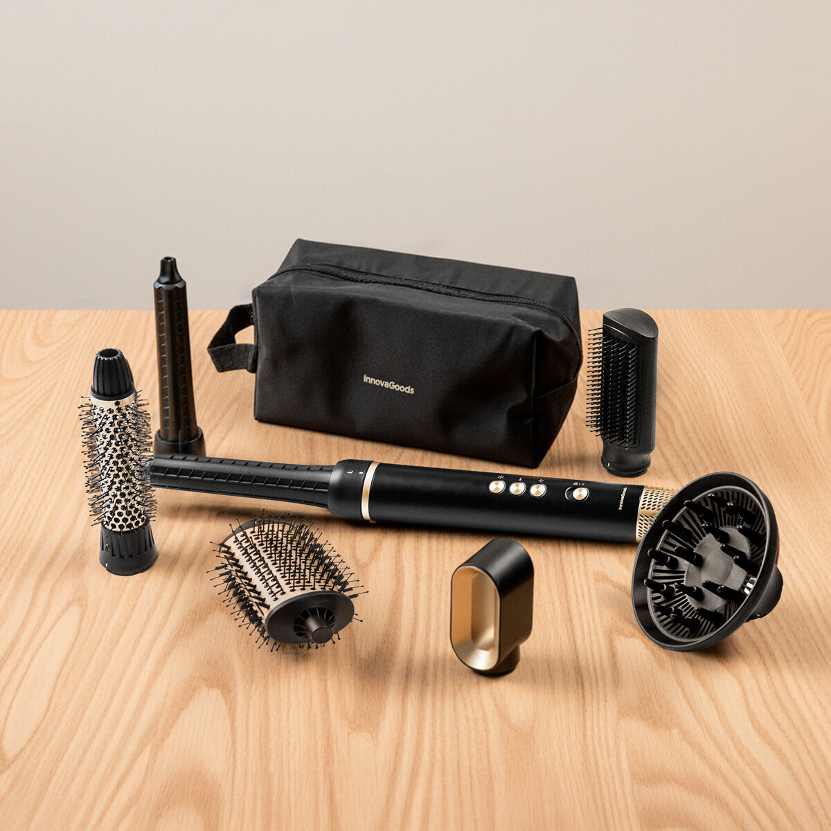 Haarstyling-Set auf einem Holztisch. Enthält einen schwarz-goldenen Haartrockner, Bürsten, Diffusoren und eine schwarze Tasche.