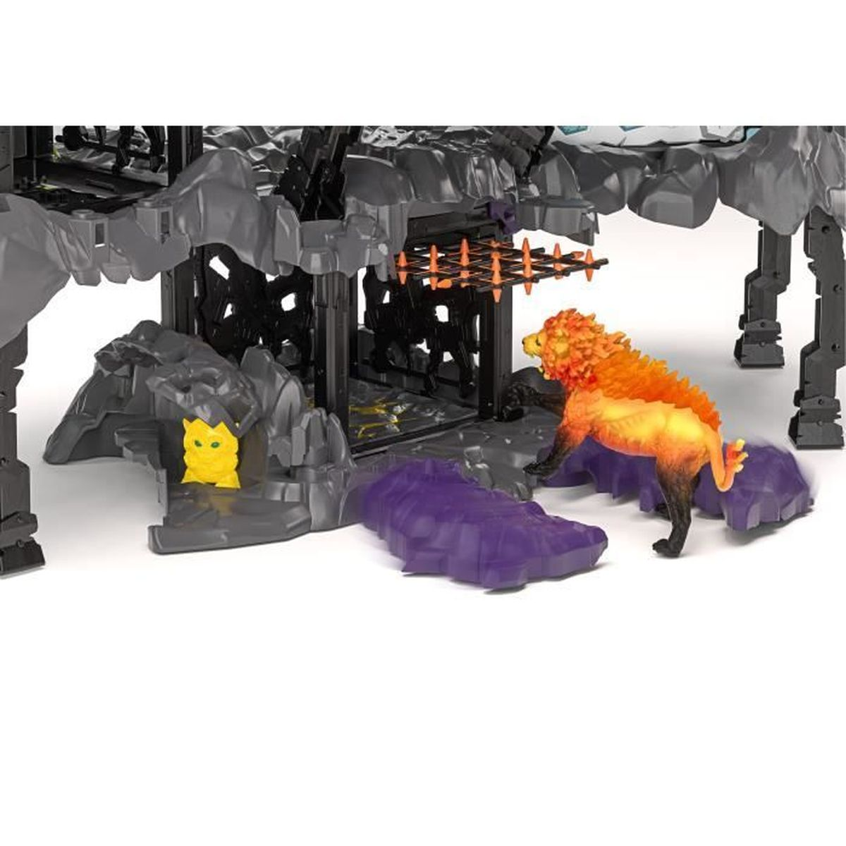Eine Spielzeugszene mit einem Löwen, einer gelben Figur und einem Käfig. Der Löwe hat eine orangefarbene Mähne und Fell. Felsen und ein Tor sind ebenfalls sichtbar.