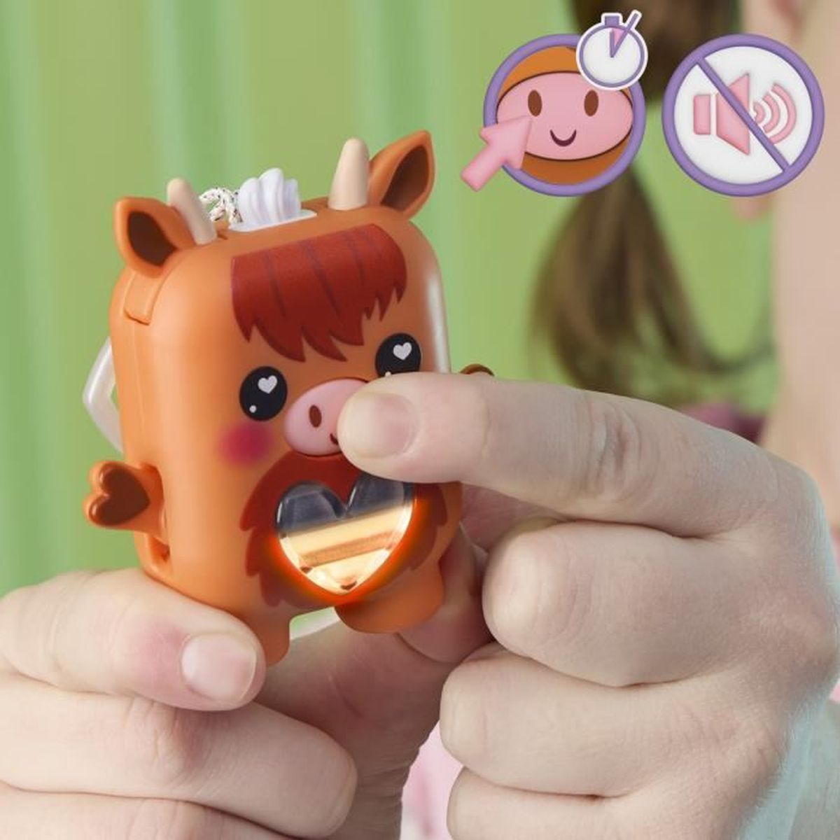 Una persona sostiene una vaca de juguete naranja con una luz en forma de corazón. El fondo incluye iconos y una pared verde.
