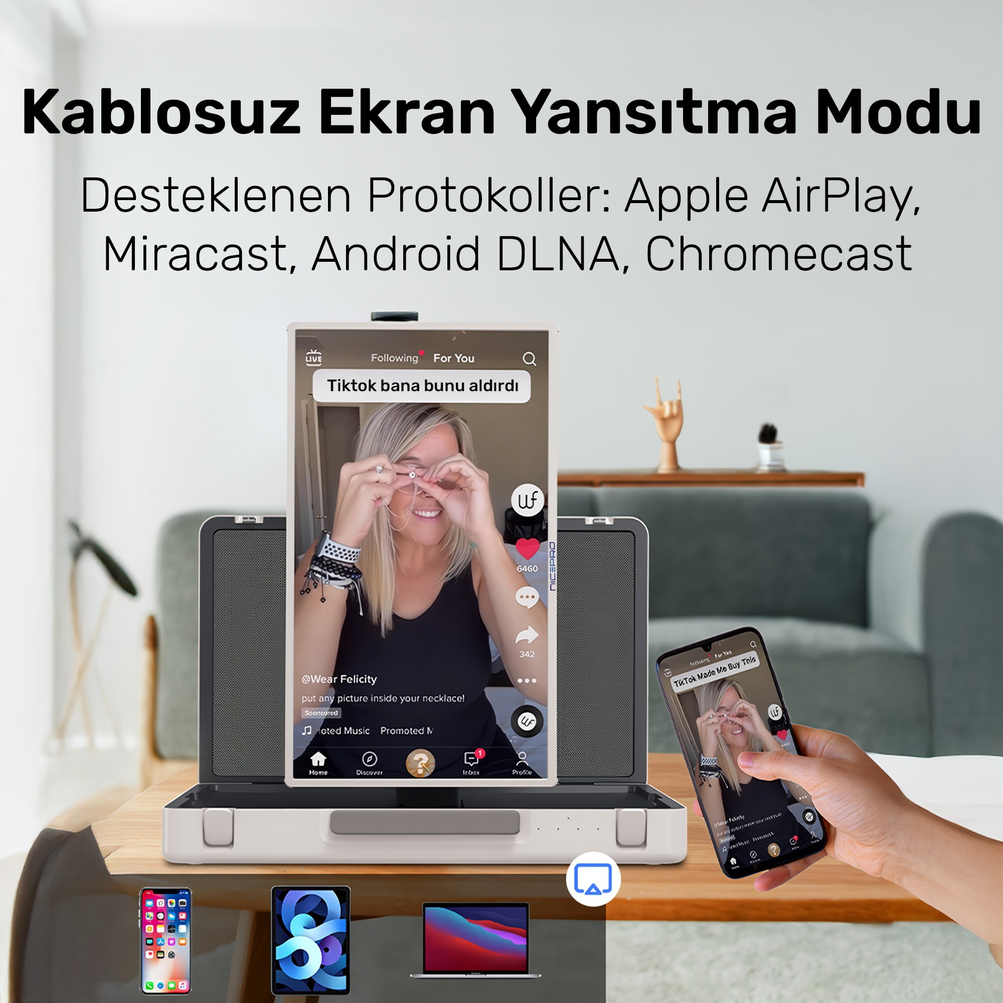 Bir ekran yansıtma cihazı bir TikTok videosu görüntülüyor. Bir telefon ve tablet masada. Bir el başka bir telefon tutuyor.