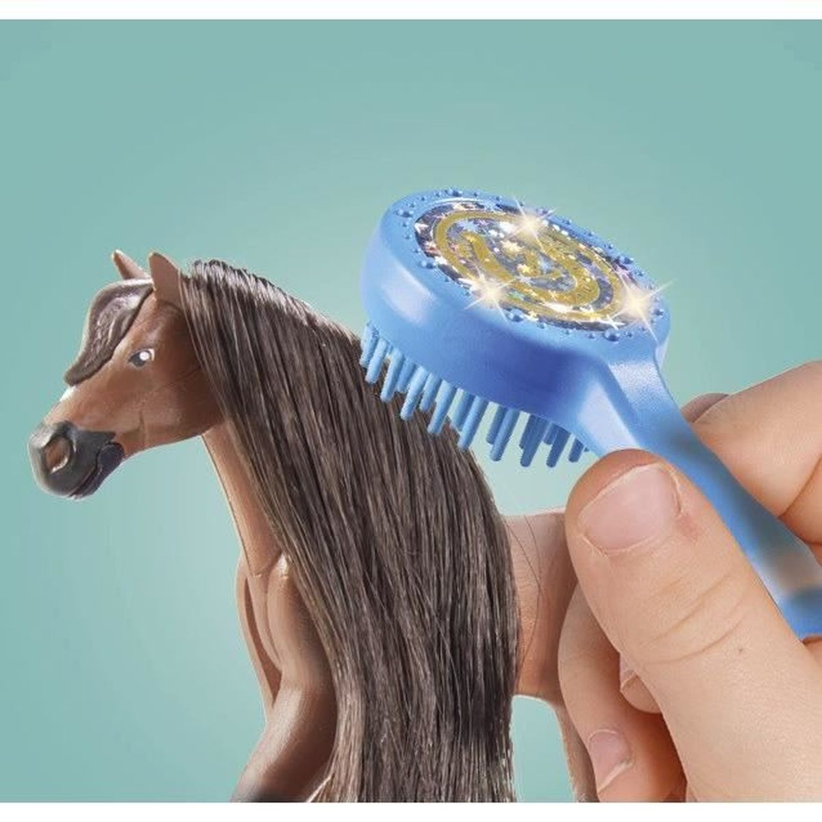 Una mano spazzola la criniera di un cavallo giocattolo marrone con una spazzola blu. La spazzola ha un design intricato.