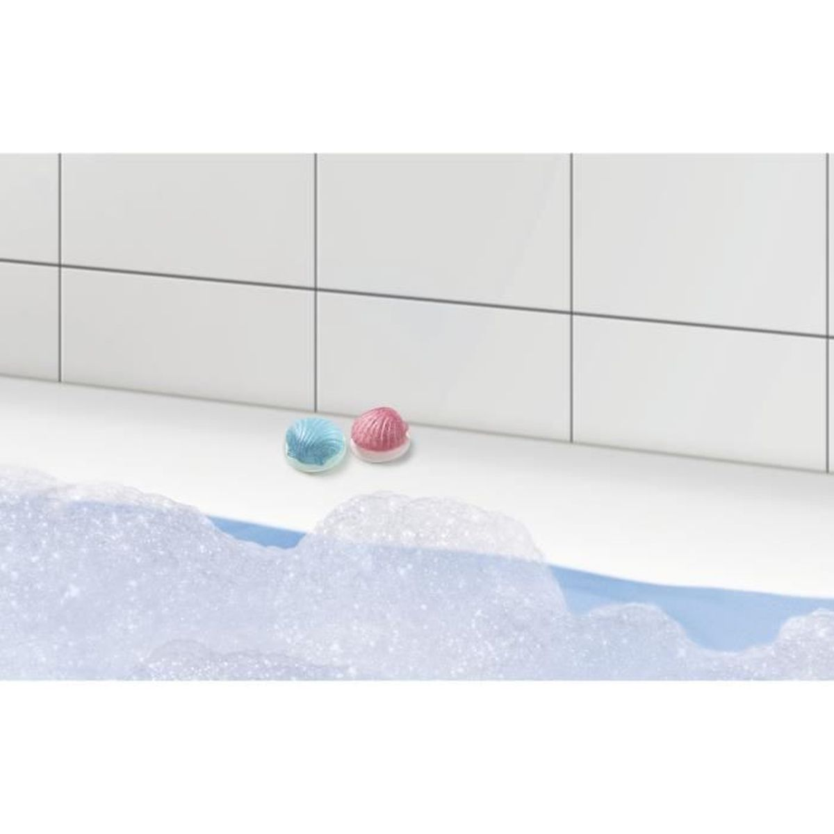 Due conchiglie decorative in una vasca da bagno con bolle. Una è blu, l'altra rosa. Piastrelle bianche sullo sfondo.
