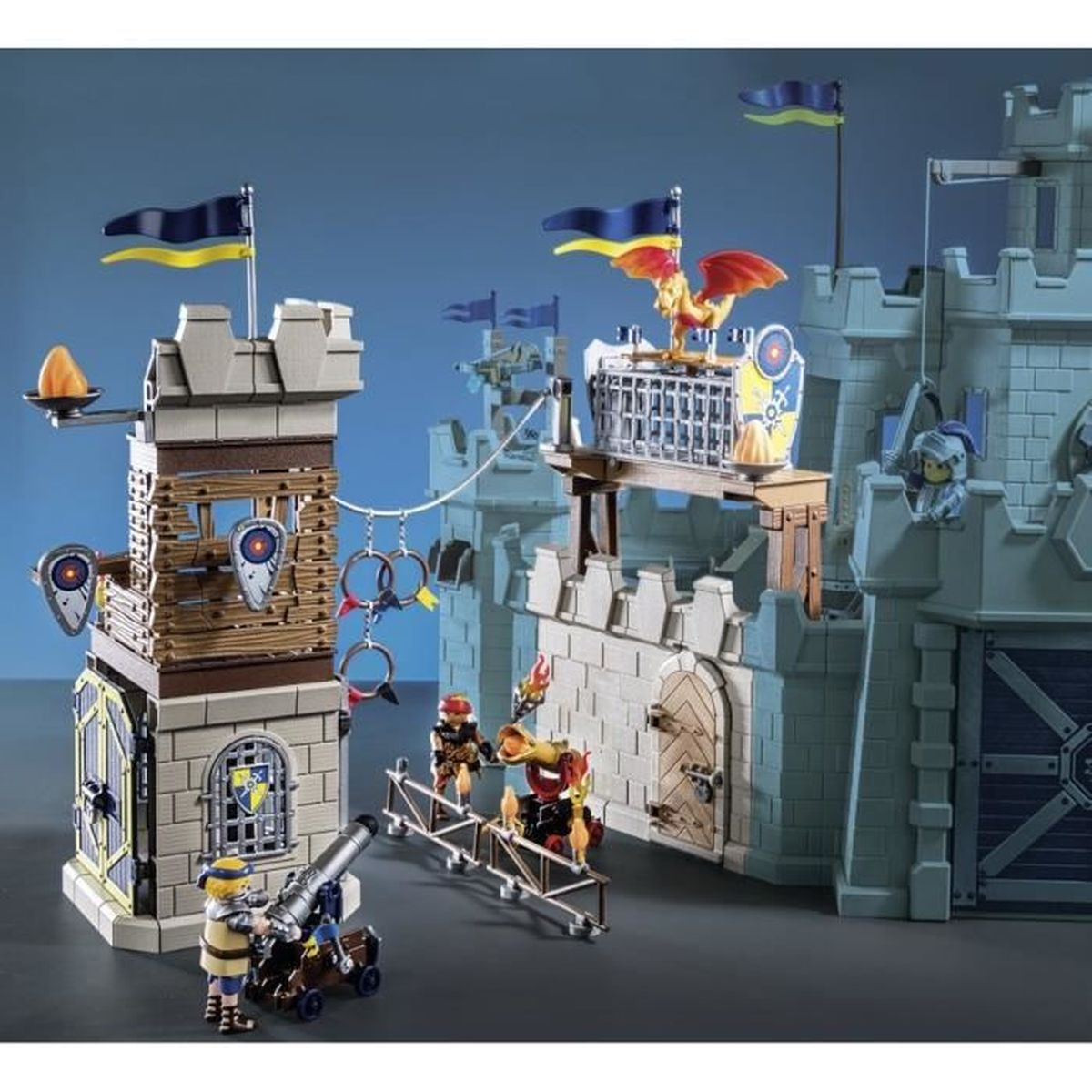Eine Spielzeugburg mit Fahnen, Figuren und einer Kanone. Ritter stehen auf einer Brücke. Eine Drachenfigur sitzt auf einem Bauwerk.