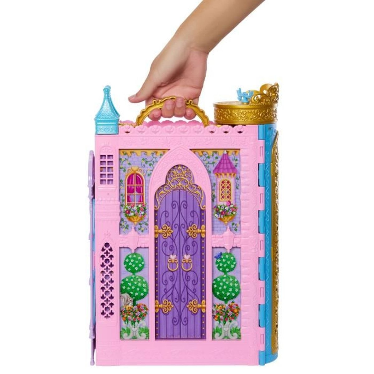 Eine Hand hält ein rosa Spielzeugschloss mit lila Tür und goldenem Griff. Es hat Fenster, Türme und ist mit floralen Details verziert.